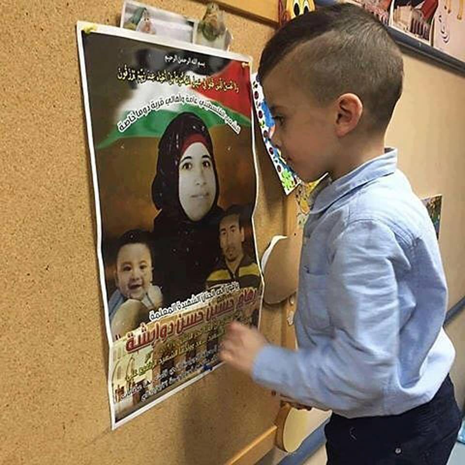 Ahmad Dawabsha looks at poster of his mom (image from family)
