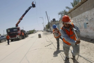 Palestinian electricity company workers drag a power line following an Israeli airstrike in the southern Gaza Strip, on Aug. 6, 2014. (AFP/Said Khatib, File)