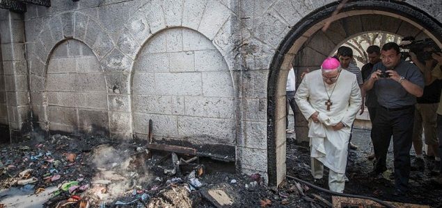 Priest inspects burned church building, June 2015