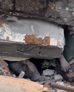 Hands visible under rubble